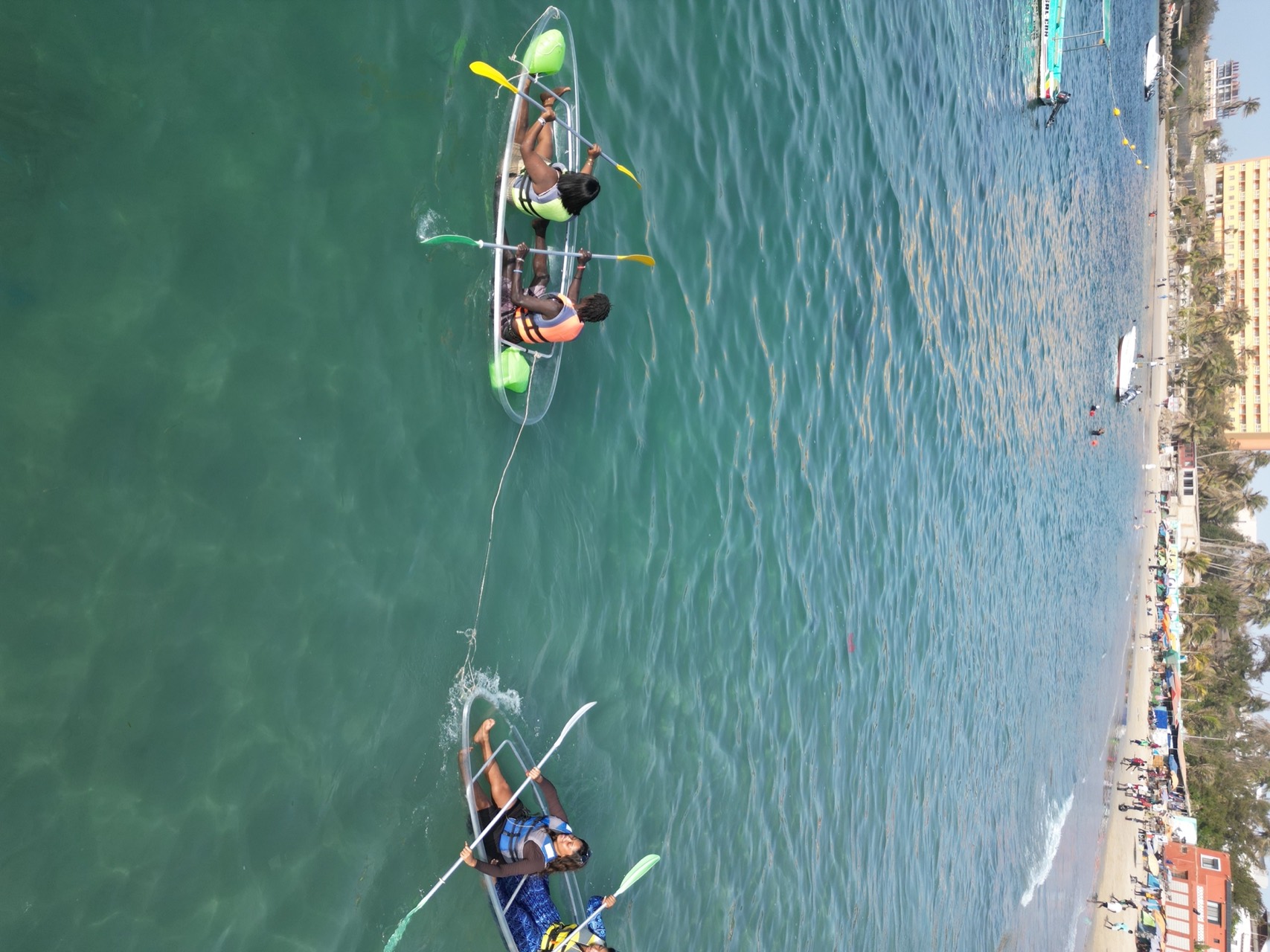 Enfants et adultes en gilet de sauvetage dans des kayaks transparents à Ngor, Dakar
