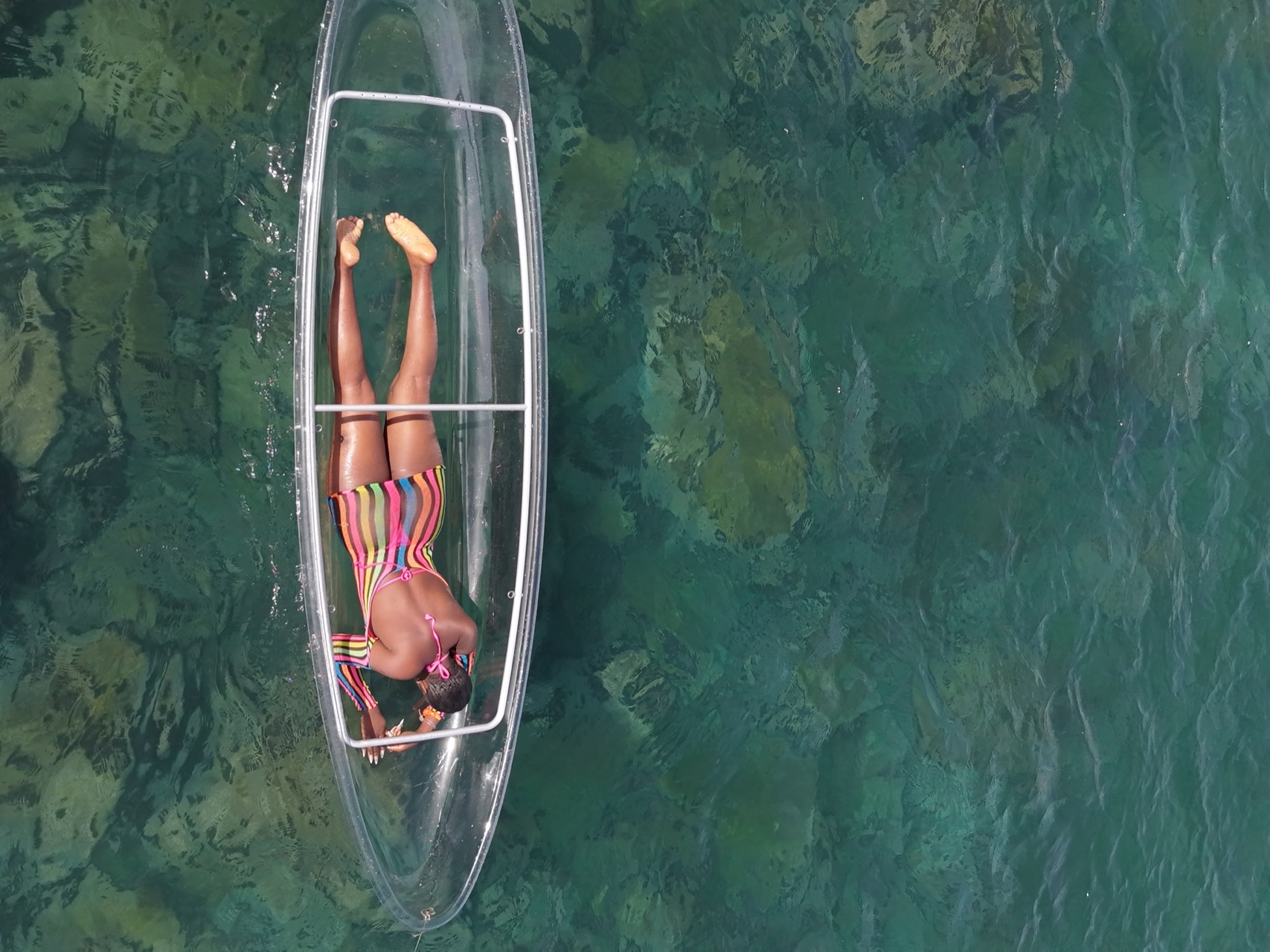 Jeune femme allongée dans un kayak transparent sur une eau cristalline au-dessus des rochers de Ouakam - Eau turquoise Dakar, Senegal Nautique